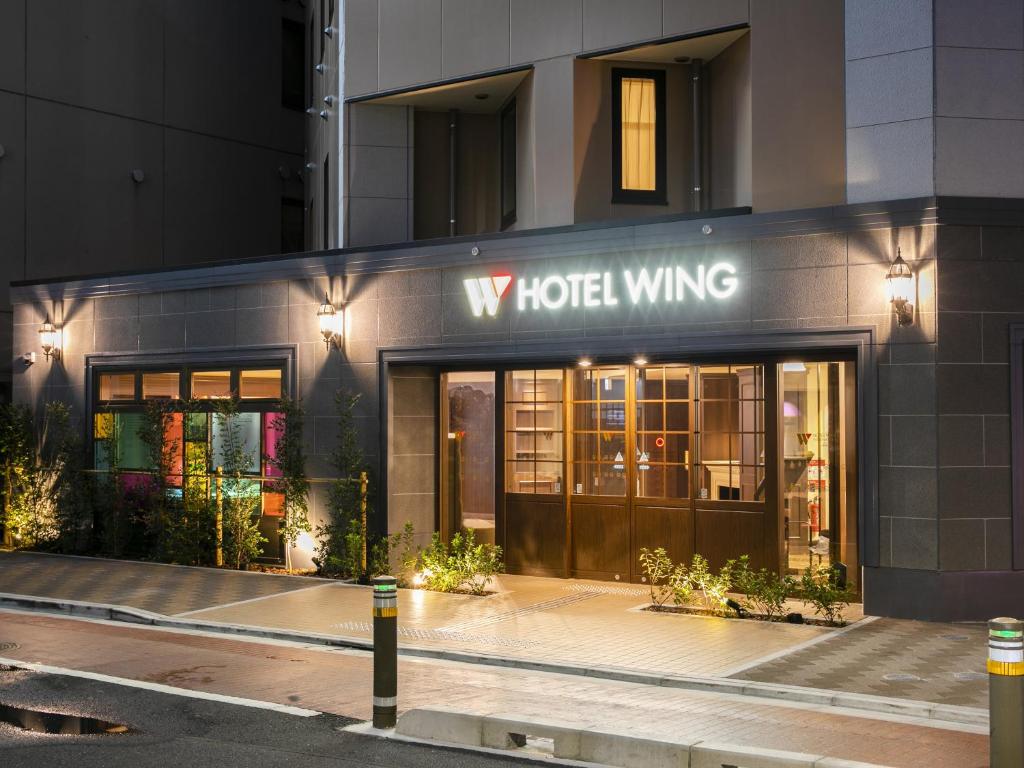 东京Hotel Wing International Select Ikebukuro的酒店大楼,上面有标牌,上面写着酒店翼楼