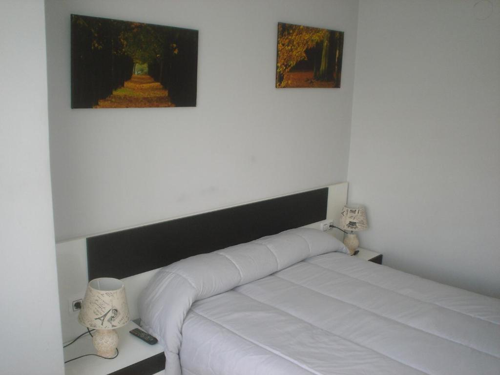 奥伦塞HOSTAL CID的墙上有两张照片的房间的一张白色床