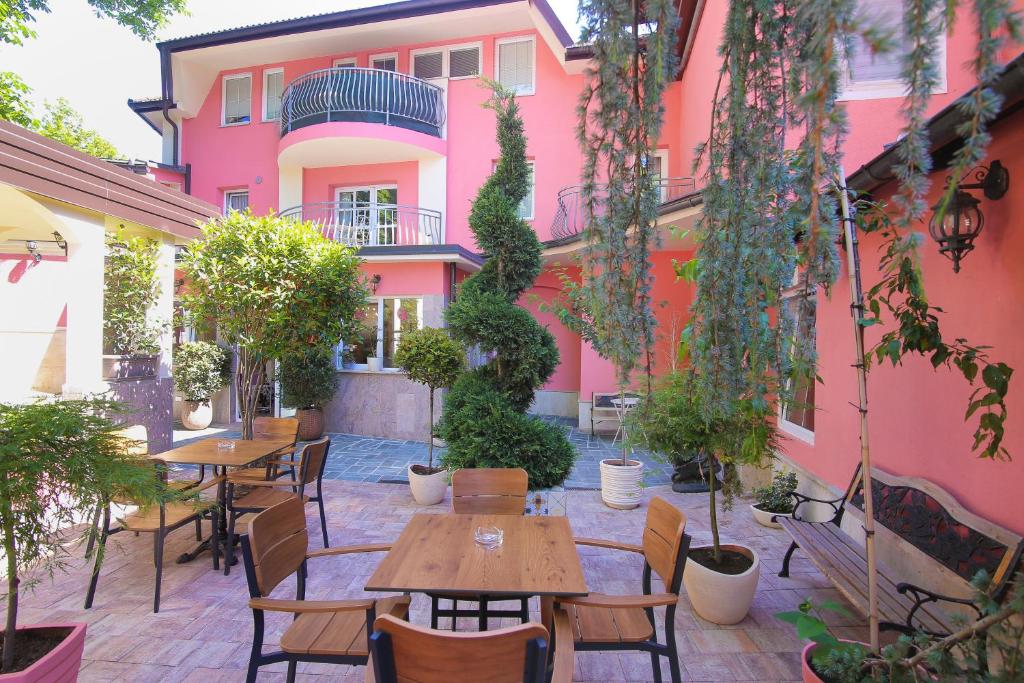 卢布尔雅那Boutique Hotel Asteria的粉红色建筑前方带桌椅的庭院