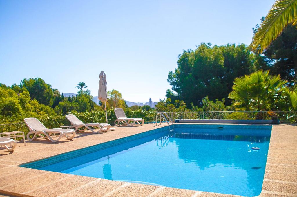 贝尼多姆Villa Altozano with pool, barbeque, large garden, and fantastic sea views的一个带两把椅子和遮阳伞的游泳池