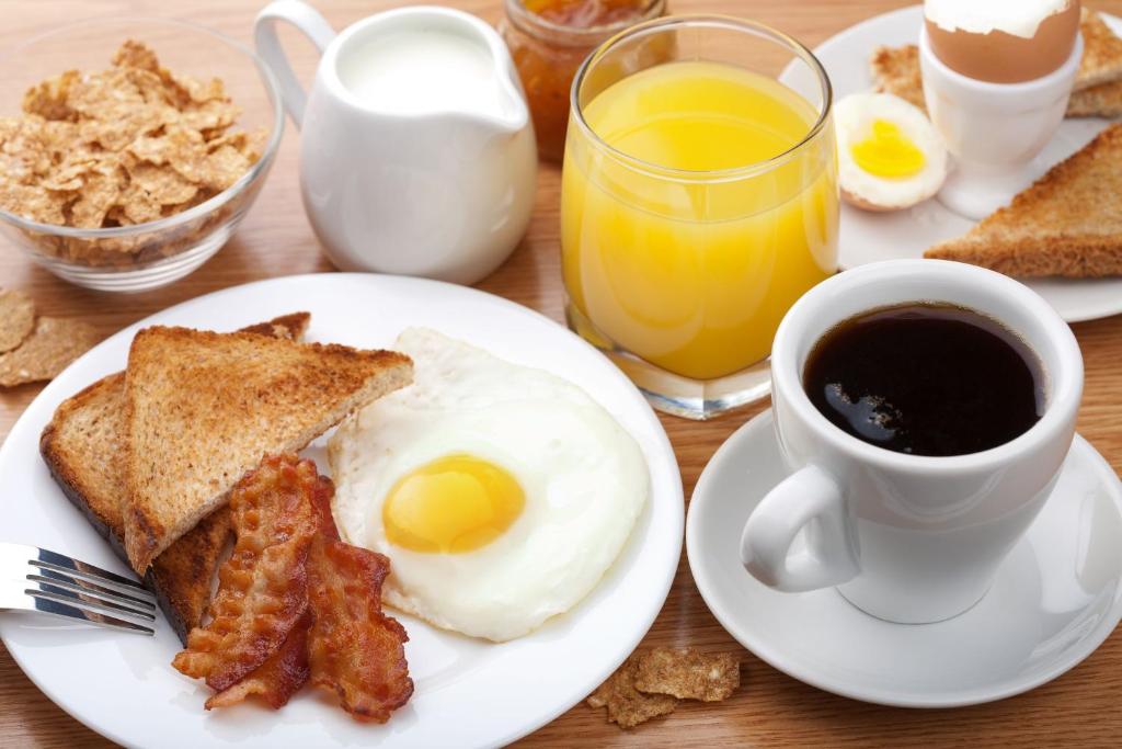 马尼萨莱斯Hotel Grato Manizales的早餐盘包括鸡蛋培根、烤面包和一杯咖啡