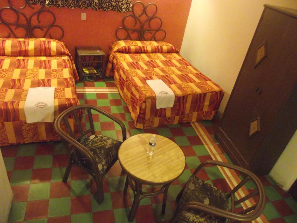 贾拉普HOTEL POSADA SANTIAGO的一间设有两张床和一张桌子及椅子的房间