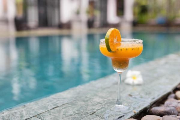 沙努尔The Bali Bubble的一杯橙汁坐在游泳池旁