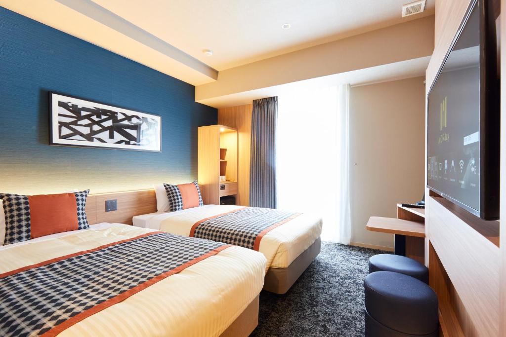 东京hotel MONday Asakusa的酒店客房设有两张床和一台平面电视。