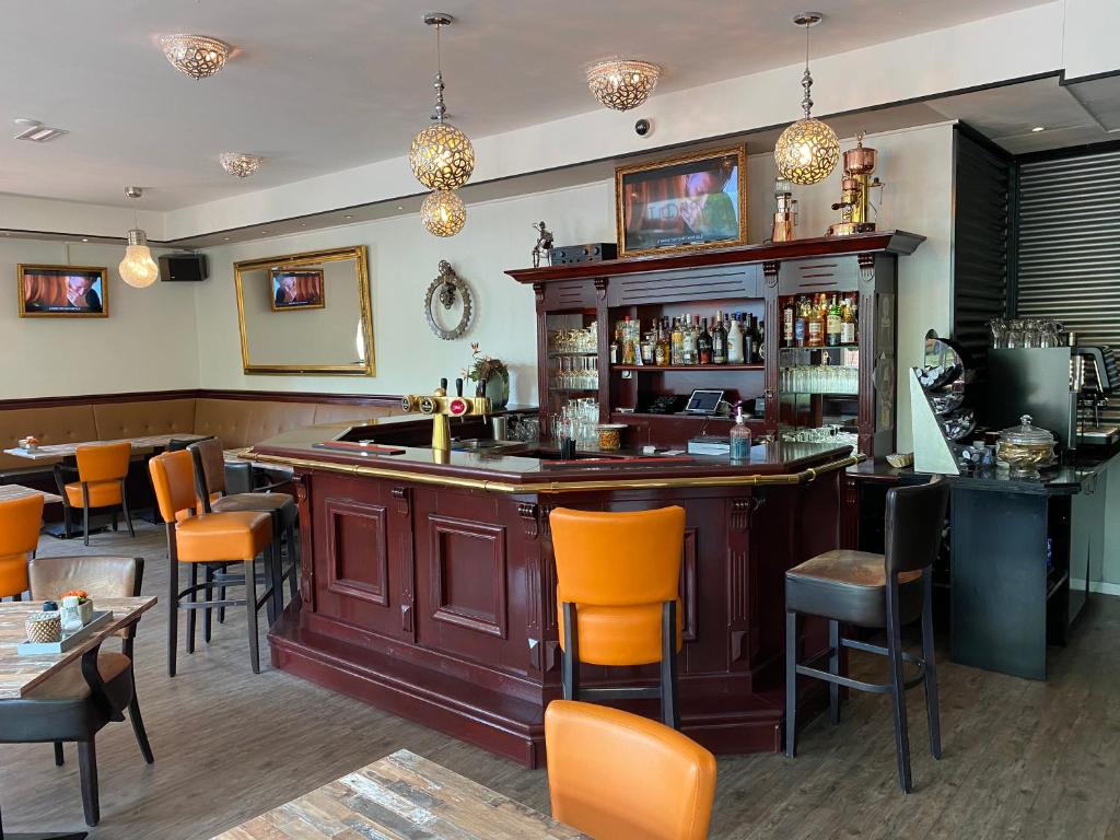斯塔茨卡纳尔City Hotel Restaurant Stadskanaal的餐厅里的酒吧,带橙色椅子