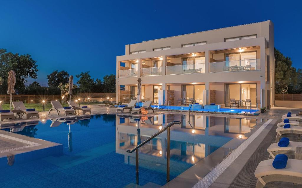 拉加纳斯Mystique Luxury Suites & Maisonettes的一座在晚上设有游泳池的大房子