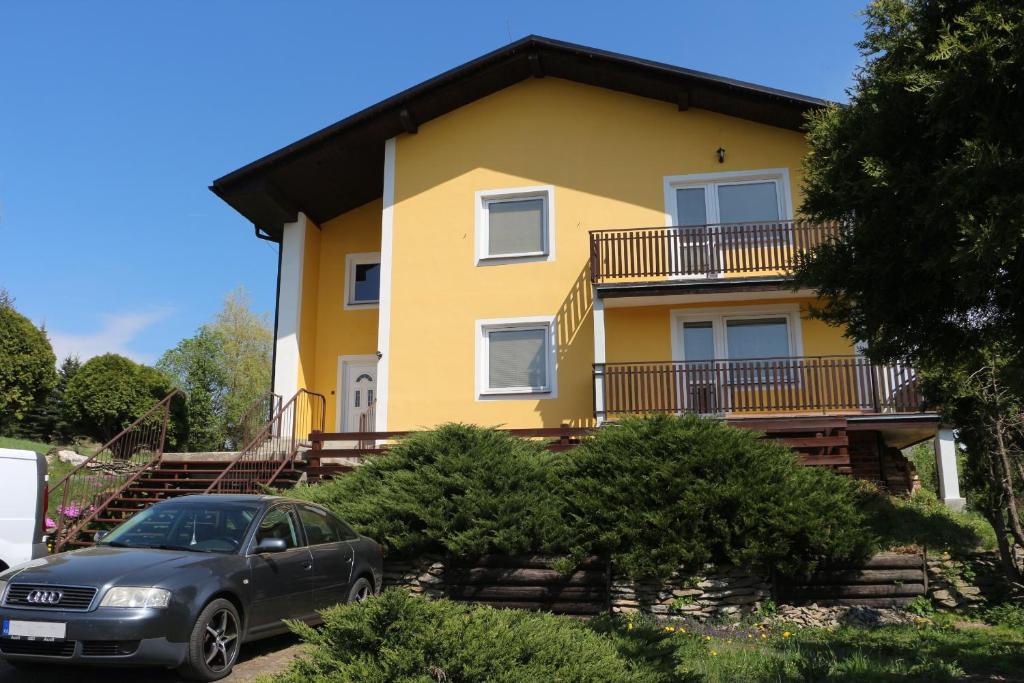 Široká NivaApartmány NIVA的一座黄色的房子,前面有一辆汽车