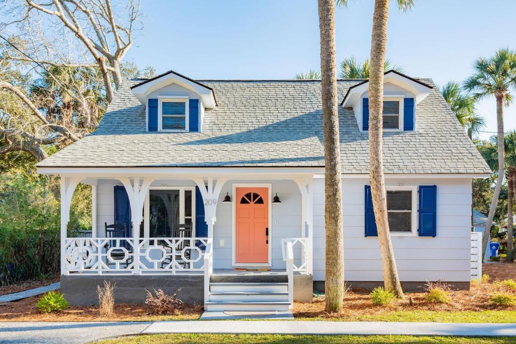 富丽海滩Folly Vacation Beautiful Beach Cottage 209-A的一座白色的房子,有红色的门和棕榈树