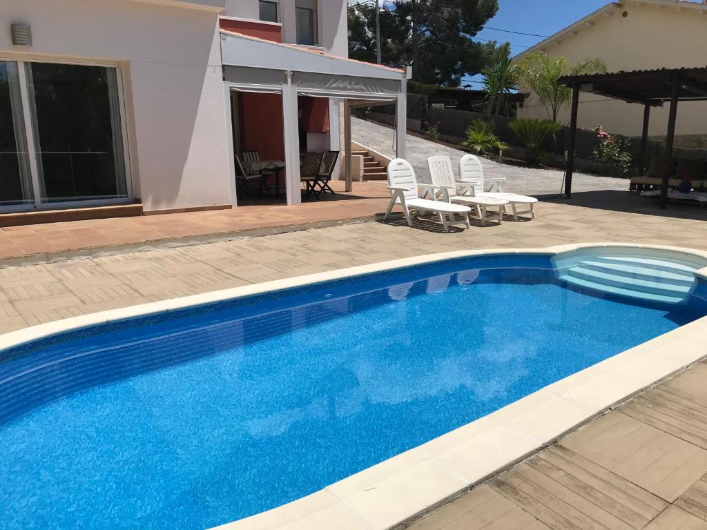 奥利维拉Villa olivella的一座大型蓝色游泳池,位于房子旁边