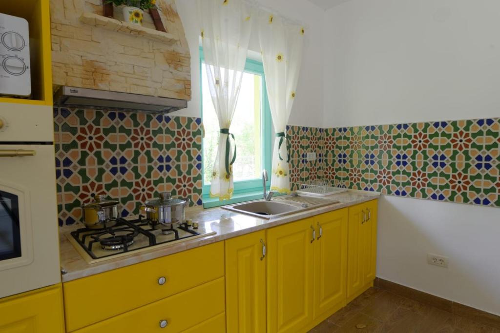 Schitu-TopolniţeiPensiunea HAPPY的厨房配有黄色橱柜、水槽和窗户。