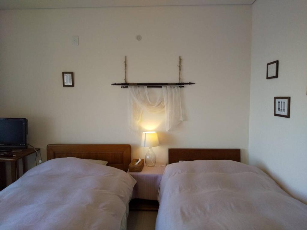 洞爷湖KEI的一间卧室设有两张床和一张桌子上的台灯。