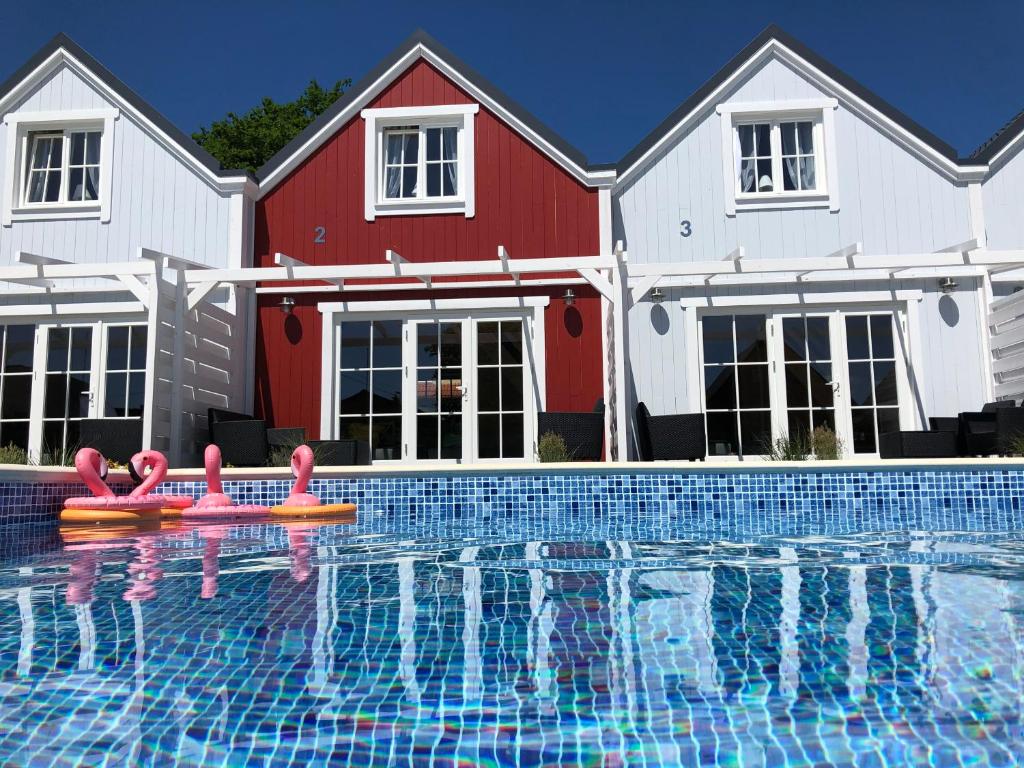 卢克钦Mamma Mia Resort的一座房子前的游泳池,游泳池内有粉红色的火烈鸟