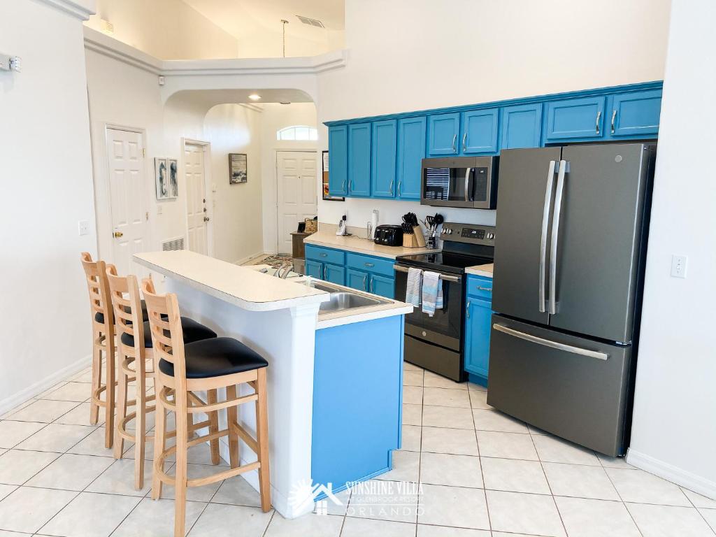 奥兰多Affordable Luxury Home Near Walt Disney World - Sunshine Villa at Glenbrook Resort, Orlando, Florida的厨房配有蓝色橱柜和黑色冰箱。