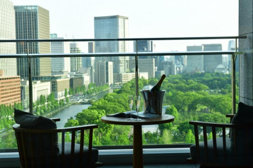 东京东京皇宫酒店的一张桌子,窗户上放着一瓶酒和一杯葡萄酒