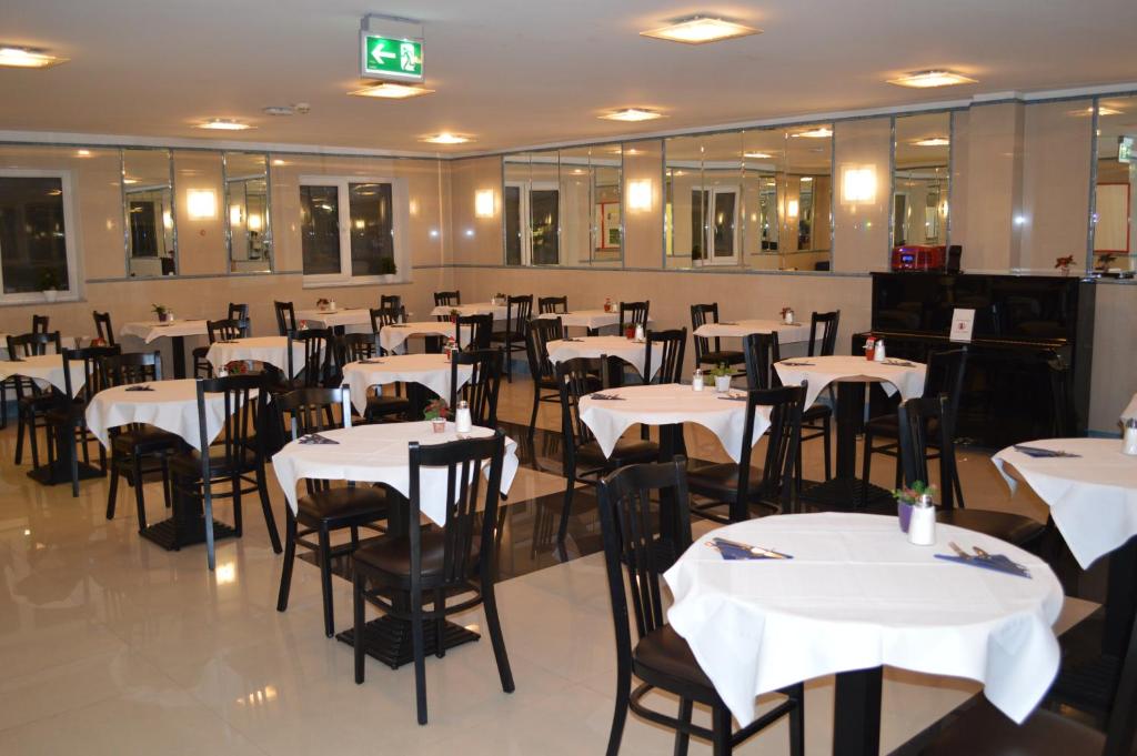 维也纳Hotel Donaustadt Kagran - at Metro U1的用餐室配有白色桌子和黑色椅子