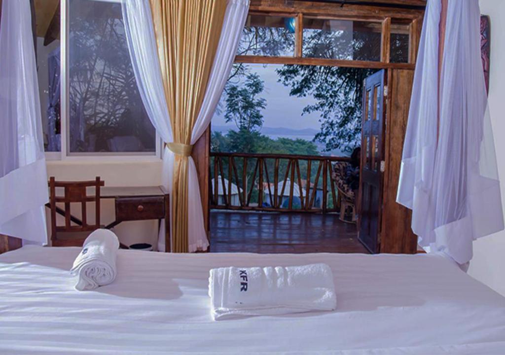 坎帕拉Kampala Forest Resort - KFR Lodge的一张带毛巾的床和一个阳台