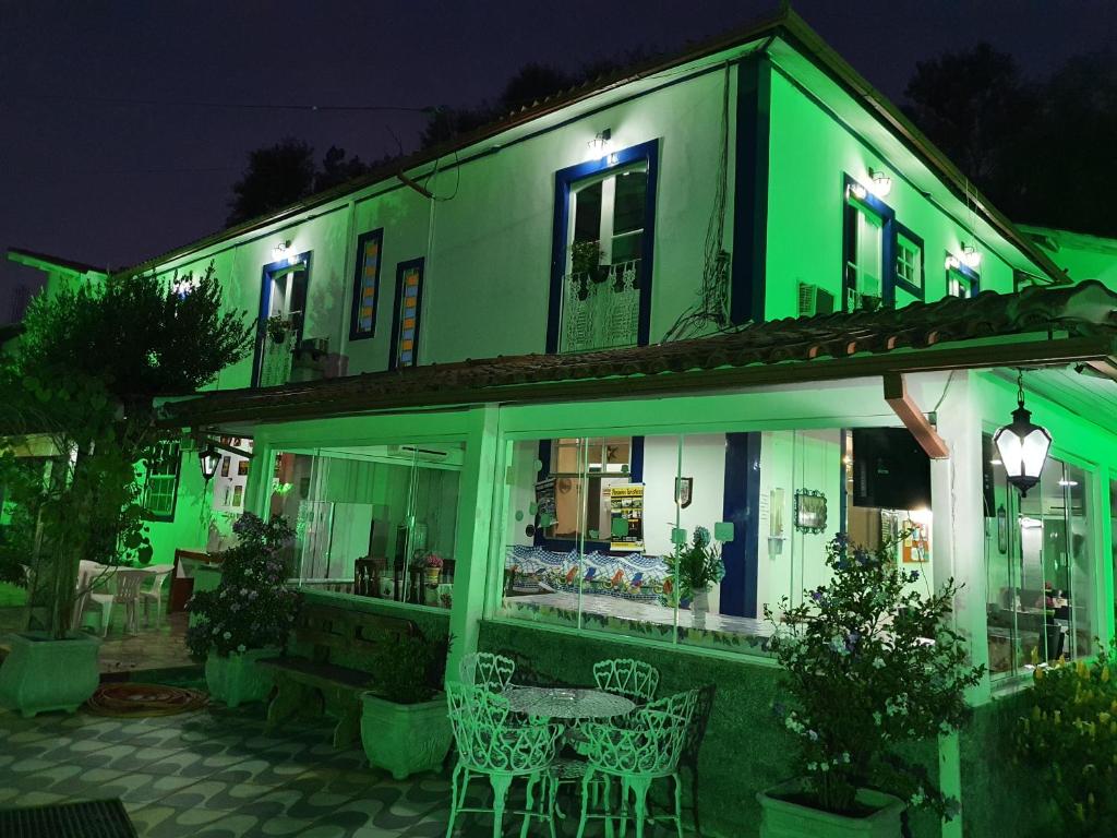 康赛瓦托利亚Pousada das Hortensias的绿色建筑,晚上配有桌椅