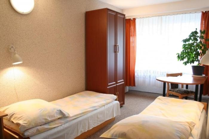 克拉科夫Hotel Biała Gwiazda的一间卧室设有两张床、一张桌子和一个窗口