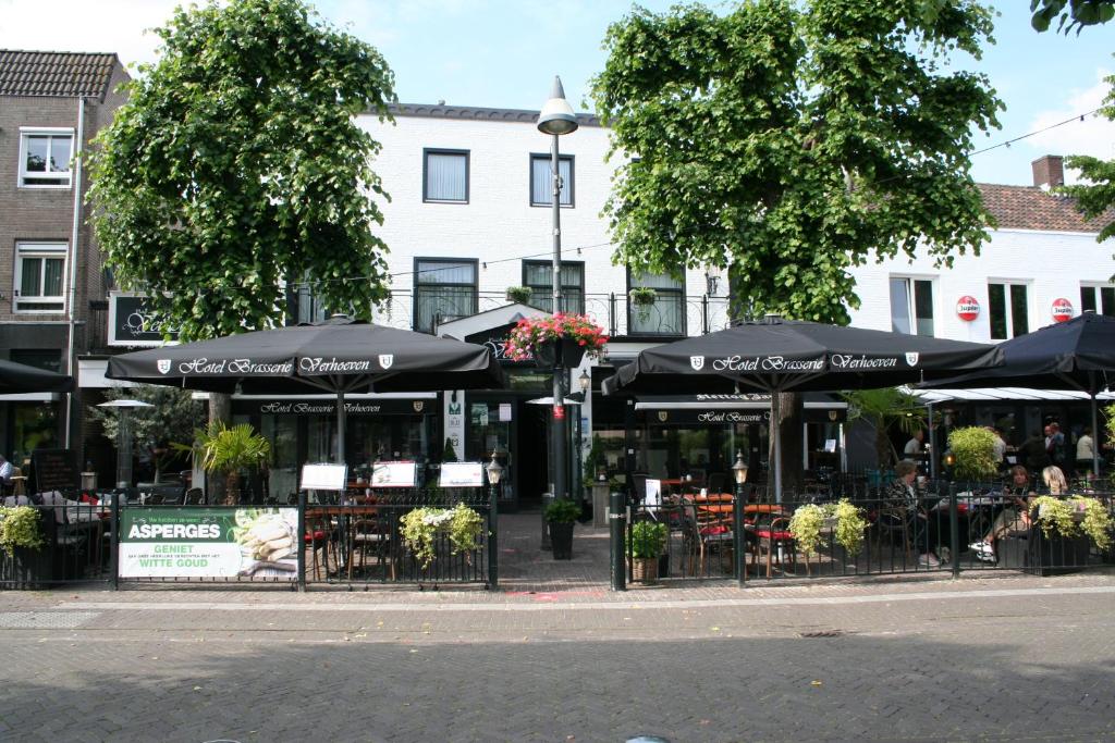 乌登Hotel Verhoeven的城市街道上带桌子和遮阳伞的咖啡厅