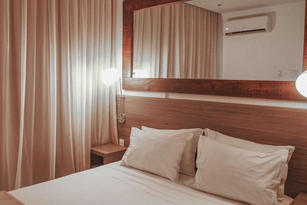 里约热内卢Samba Rio Convention & Residence的一间卧室配有一张带白色枕头和镜子的床