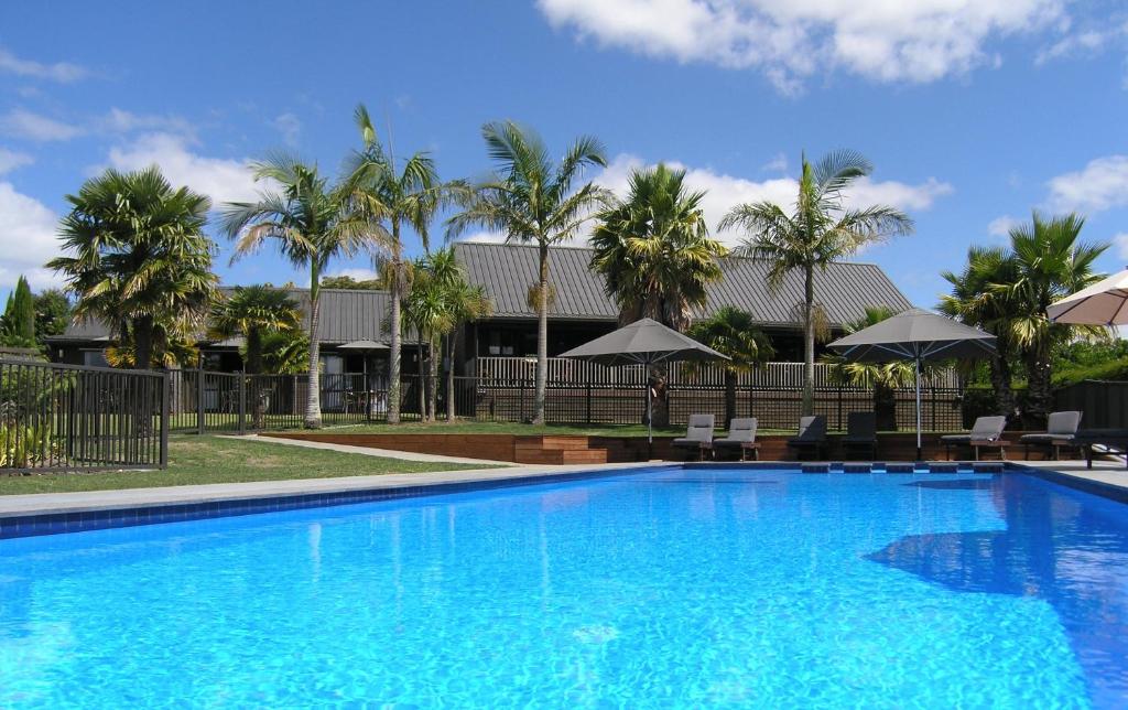 凯里凯里凯里凯里家园汽车旅馆公寓的一座种植了棕榈树和遮阳伞的大型蓝色游泳池