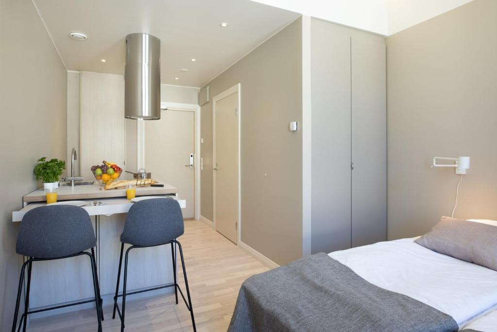 瓦萨Forenom Aparthotel Vaasa的一间卧室配有一张床和两把椅子,还设有一间厨房