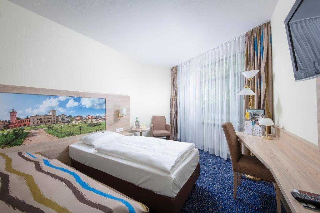柏林格鲁内瓦尔德景观酒店的酒店客房设有一张床,墙上挂有绘画作品