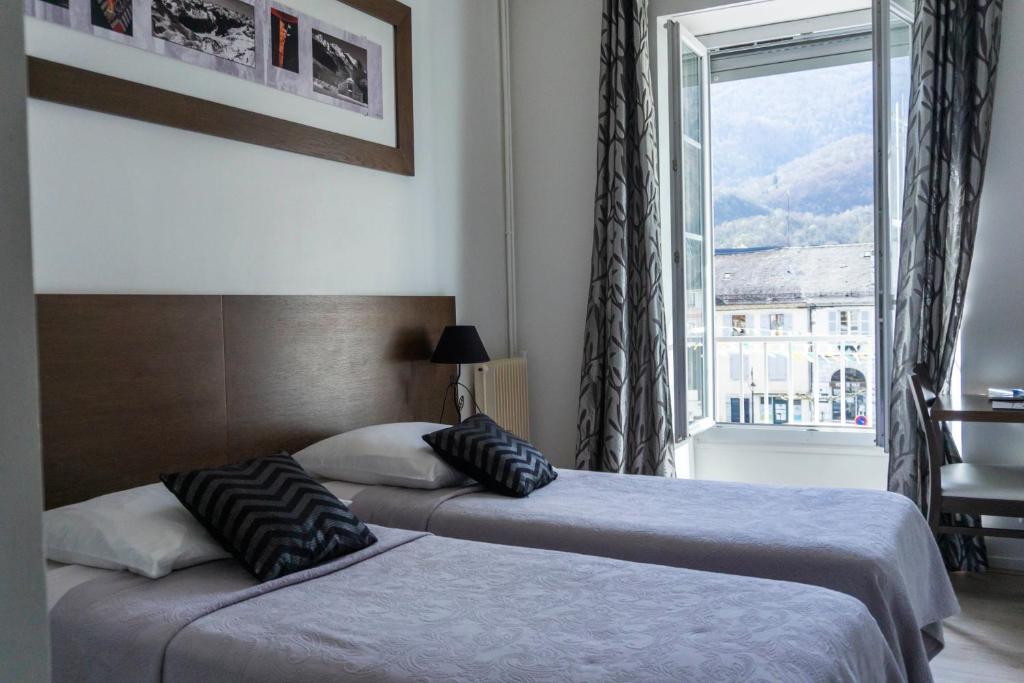 拉兰Hôtel d'Ossau的配有窗户的酒店客房内的两张床