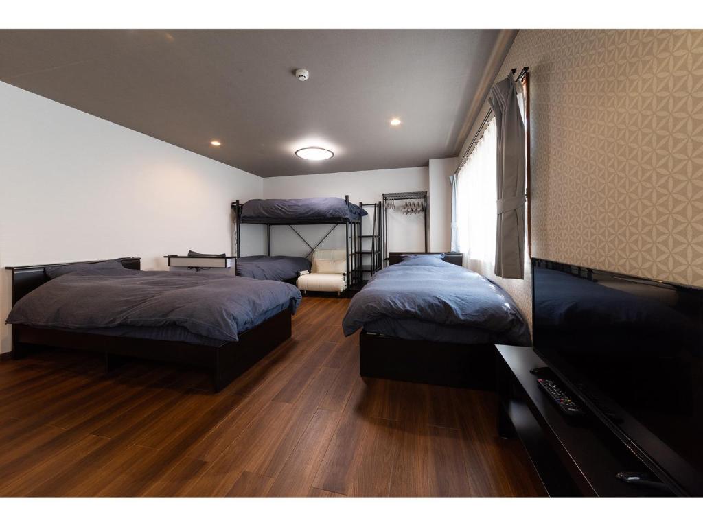 东京Oyado Kien Ryogoku的一间卧室配有两张床和一台平面电视