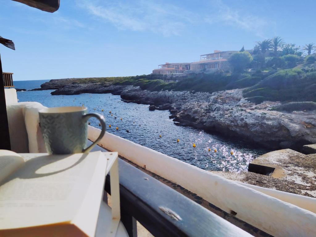 比尼贝卡Fantástica casa a primera línea de mar en Binibeca的咖啡杯坐在阳台上,俯瞰一排水面