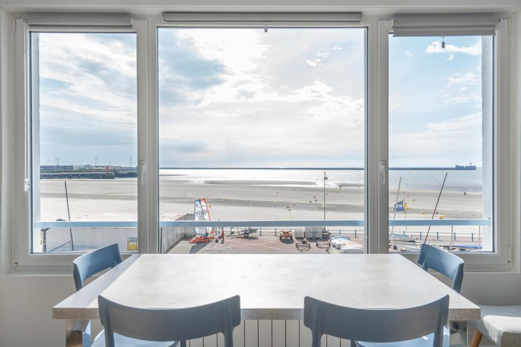 滨海布洛涅"Les Mouettes"的一间设有一张桌子并享有海滩美景的用餐室