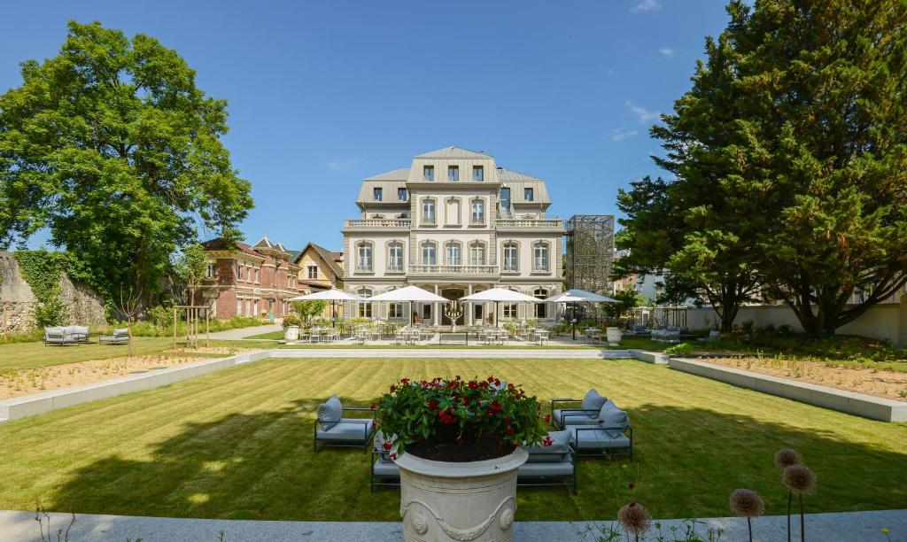 瓦龙Hôtel Mille Pas的一座大型白色房子,设有带沙发的庭院