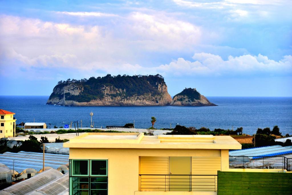 西归浦市济州巴达维阿酒店的享有海洋岛屿景致的黄色建筑