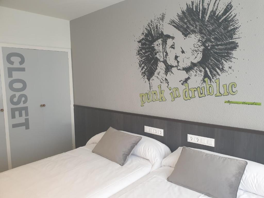 维多利亚-加斯特伊兹Hotel Arts - Gasteiz Centro的两张床铺,位于酒店房间,墙上挂着狮子