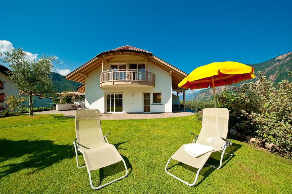 奥拉Villa Trogerhof的房子的院子内有两把椅子和一把伞