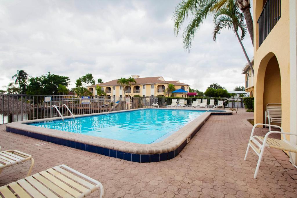 珊瑚角OYO Waterfront Hotel- Cape Coral Fort Myers, FL的一个带椅子和棕榈树的度假村的游泳池