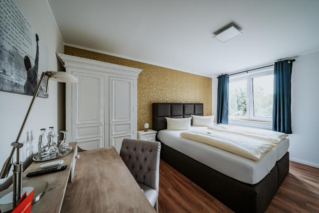 希登豪森RobrookS Hotel Garni的酒店客房设有一张大床和一张书桌。