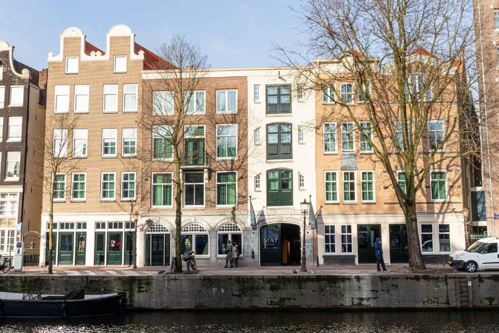 阿姆斯特丹Hotel Mai Amsterdam的河岸边的建筑物,有船