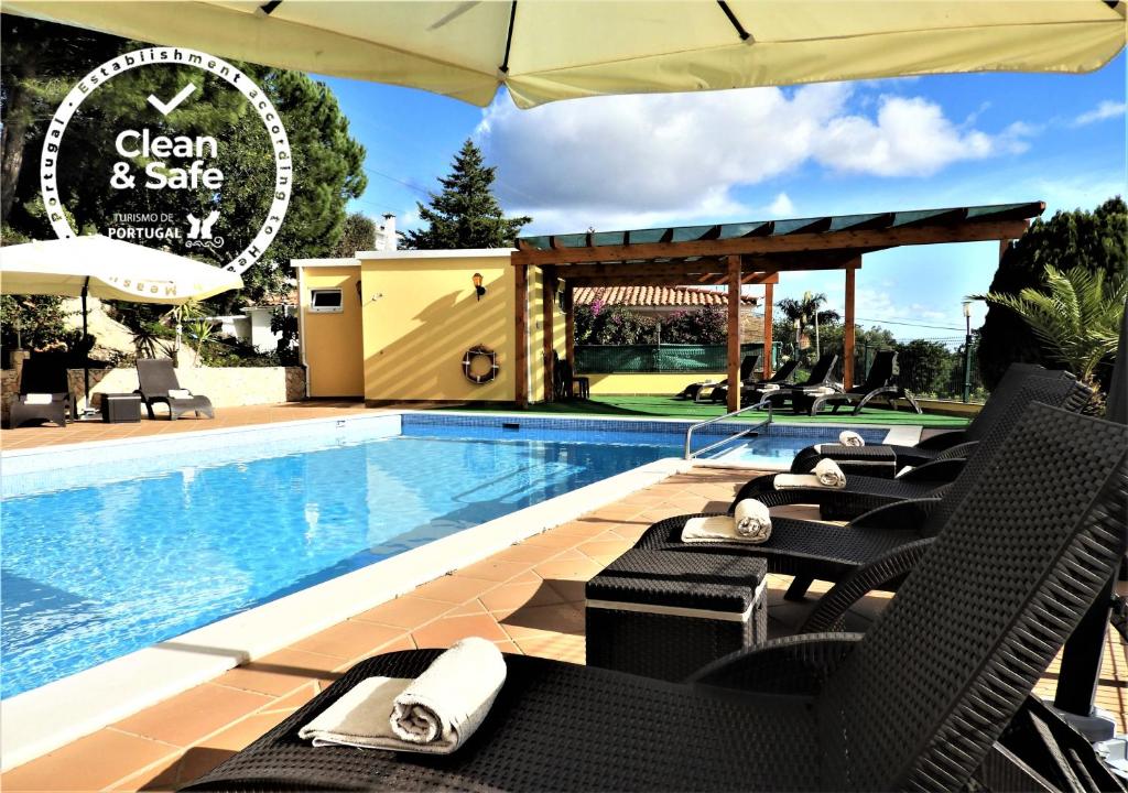 圣布拉什迪阿尔波特尔Hotel Rural Rocha da Gralheira的游泳池旁的游泳池配有椅子和遮阳伞