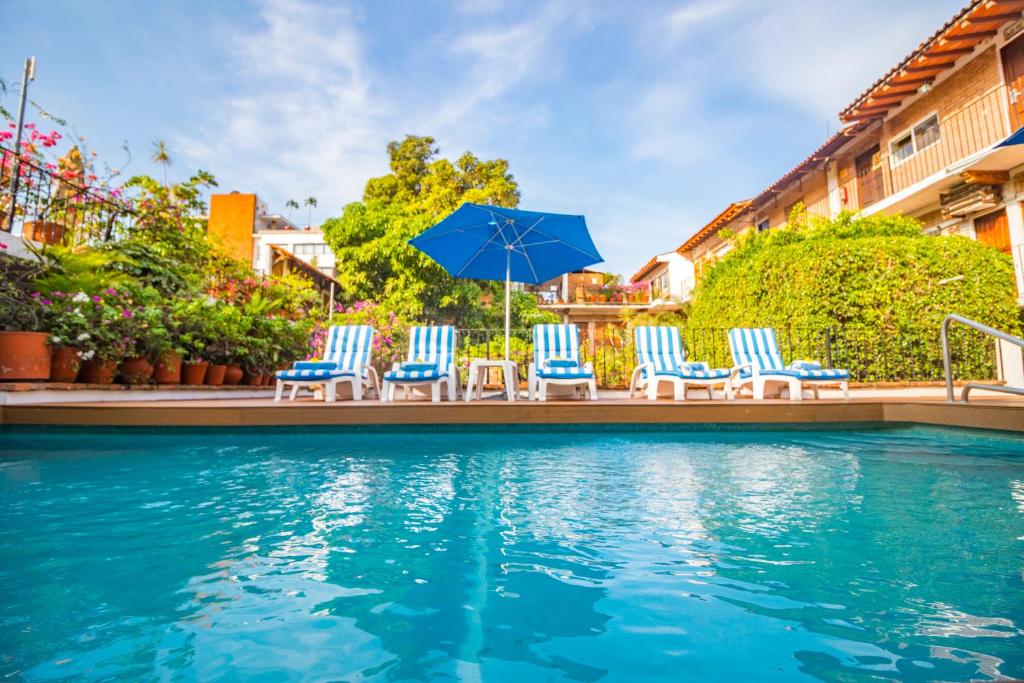 巴亚尔塔港波萨达德罗杰酒店的一组椅子和遮阳伞,位于游泳池旁