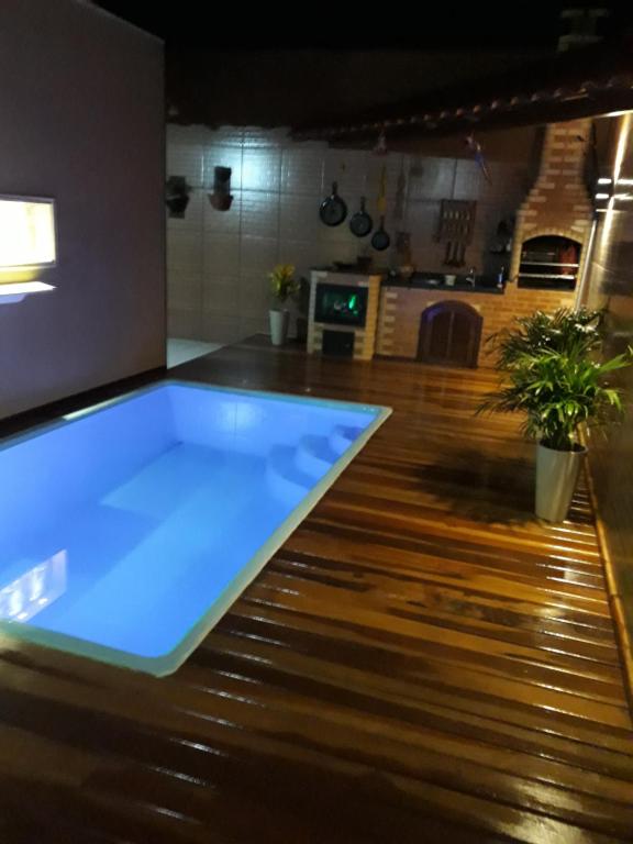 圣佩德罗-达阿尔德亚casa sao pedro da aldeia的客房铺有木地板,设有大型蓝色游泳池。