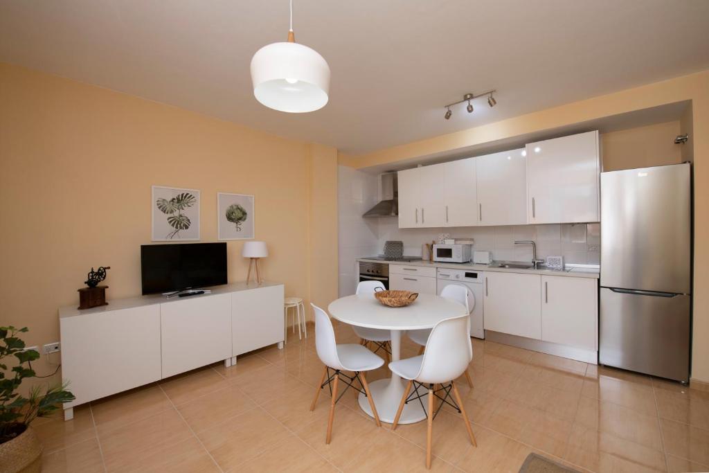 戈梅拉岛圣塞瓦斯蒂安Miramar 1的厨房配有白色橱柜和桌椅