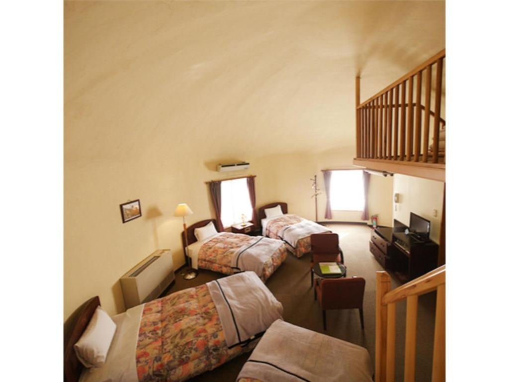 伊豆TOKINOSUMIKA HOTEL OLIVE NO KI - Vacation STAY 83624的酒店客房设有三张床和楼梯。