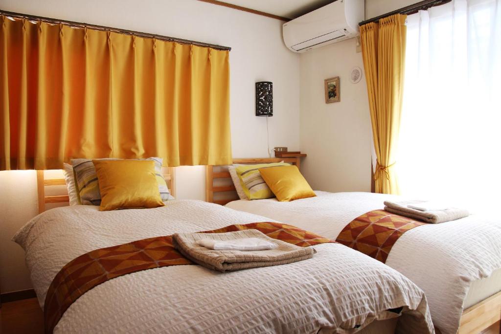 东京HAMA HILLS Shinjuku的配有黄色窗帘的客房内的两张床