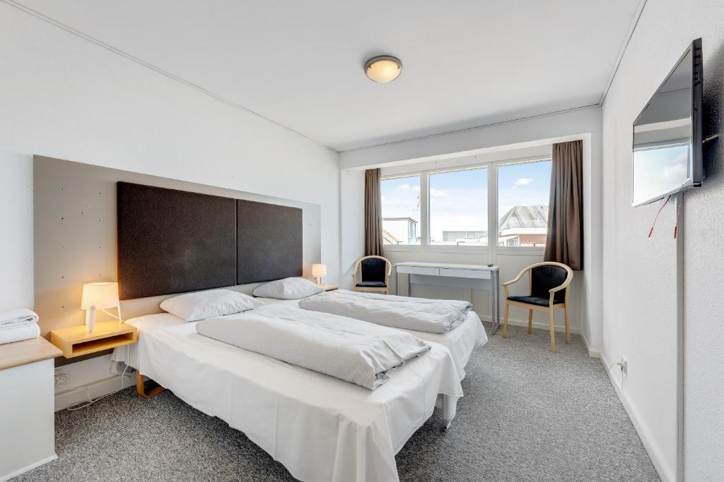 维泽桑讷维泽桑讷酒店的一间卧室设有两张床、一张桌子和窗户。