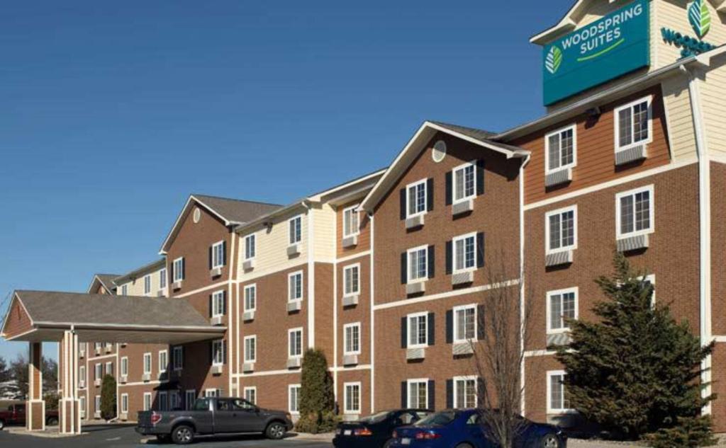 伯利恒WoodSpring Suites Allentown Bethlehem的一座大型砖砌建筑,停车场内有车辆停放