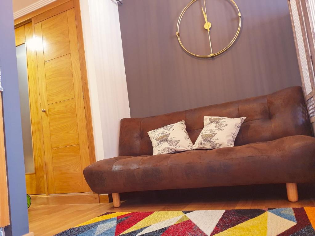 维戈Estudio Vigo Centro Lux的客厅里一张棕色的沙发,配有时钟