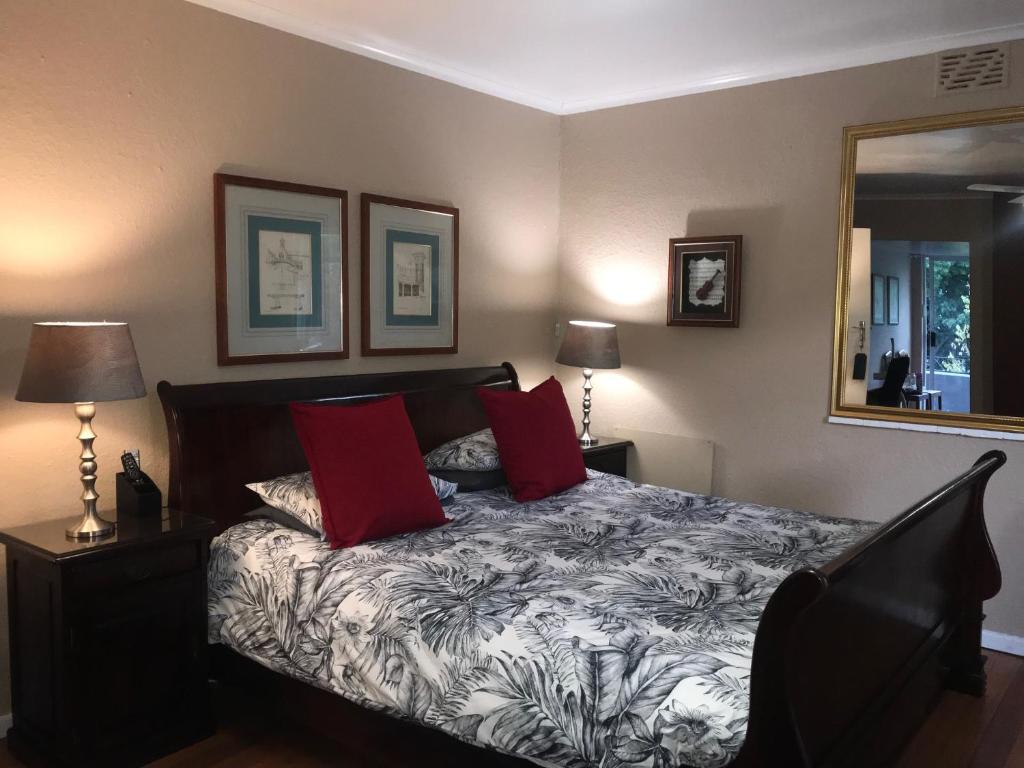开普敦Authentic Newlands的一间卧室配有一张带红色枕头和镜子的床