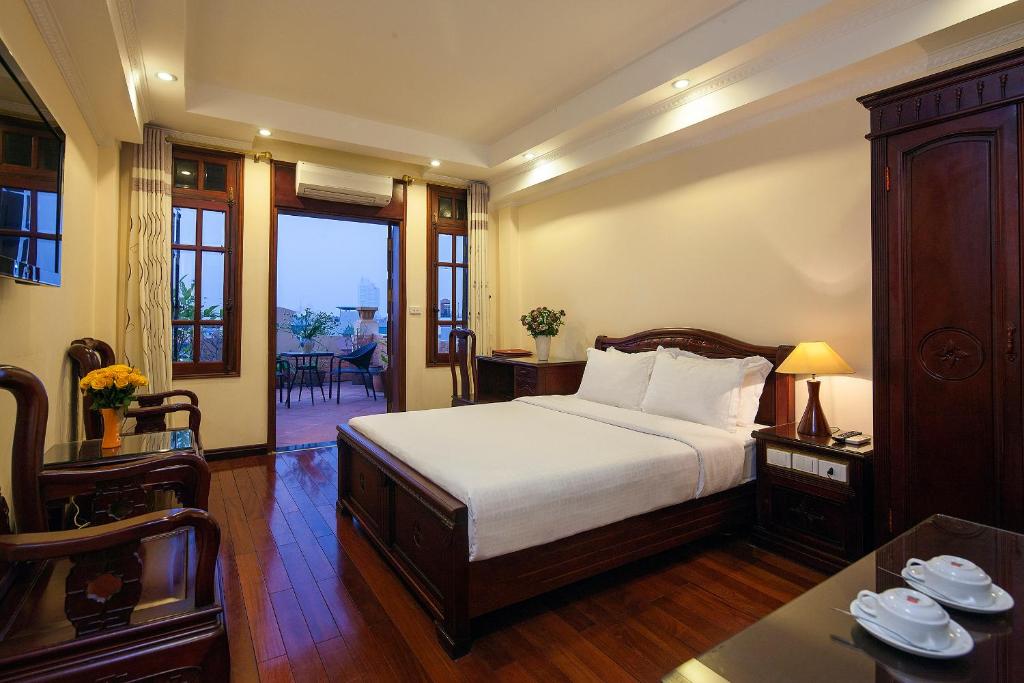 河内Lucky 3 Hotel & Travel的一间卧室配有一张大床和一张桌子及四柱床