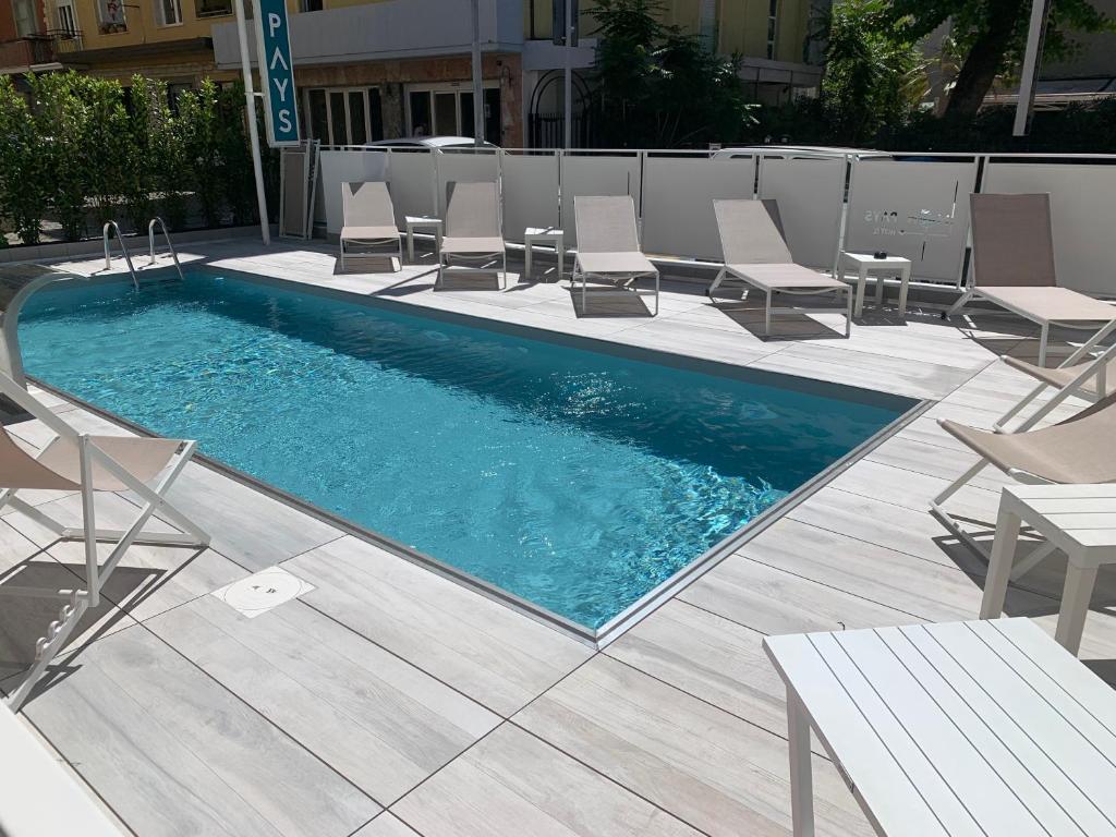 里米尼Hotel Mon Pays的一个带椅子和桌子的游泳池